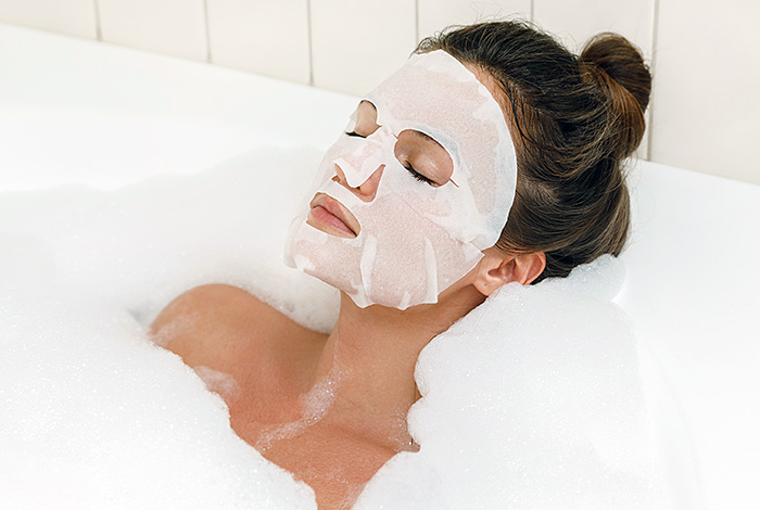 Женщина в ванной в маске для лица